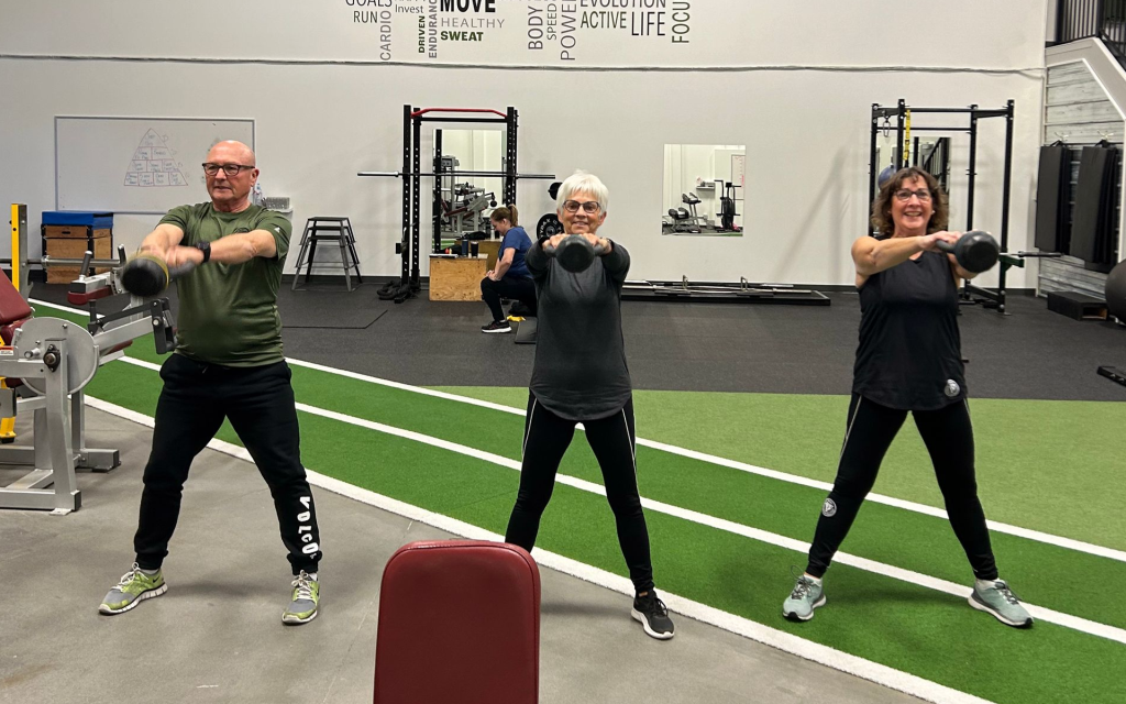 three people doing kettle bell exercises together